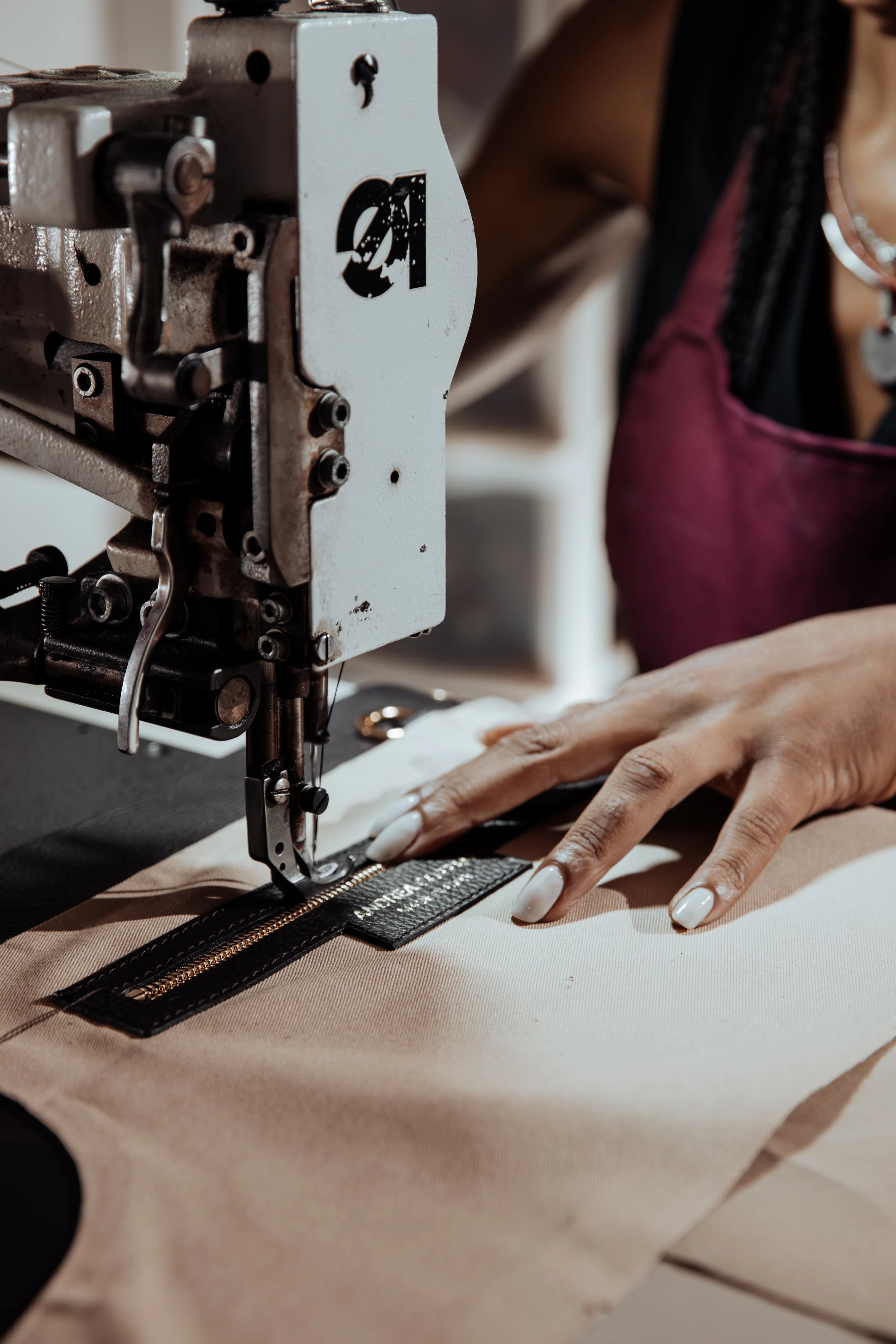 Artigiana cuce il label Andrea Coppari Milano su accessorio in pelle con macchina da cucire industriale